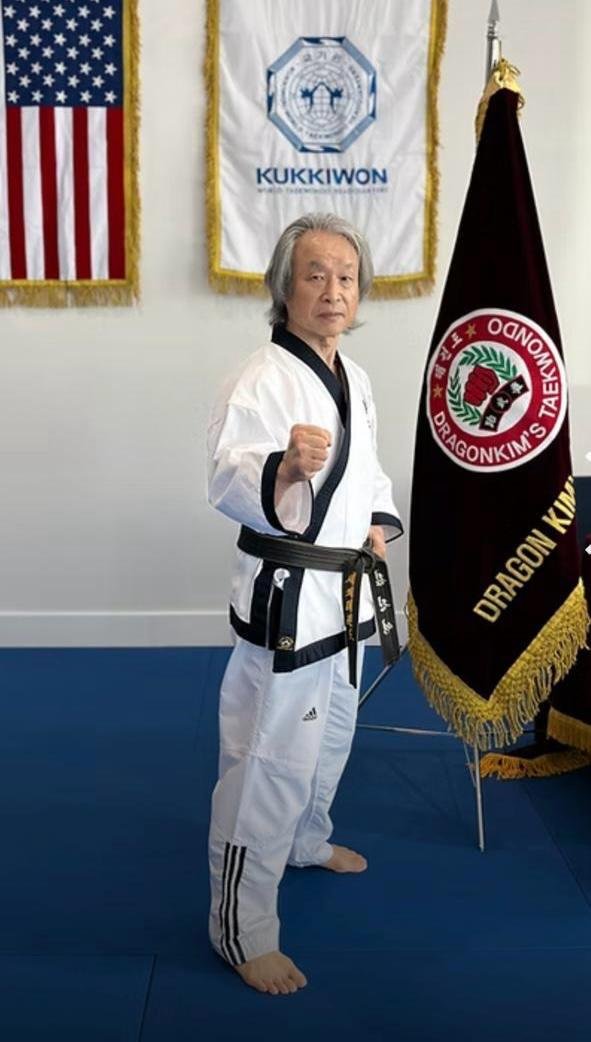 Gran Maestro con banderas de Kukkiwon y Dragon Kim's Taekwondo